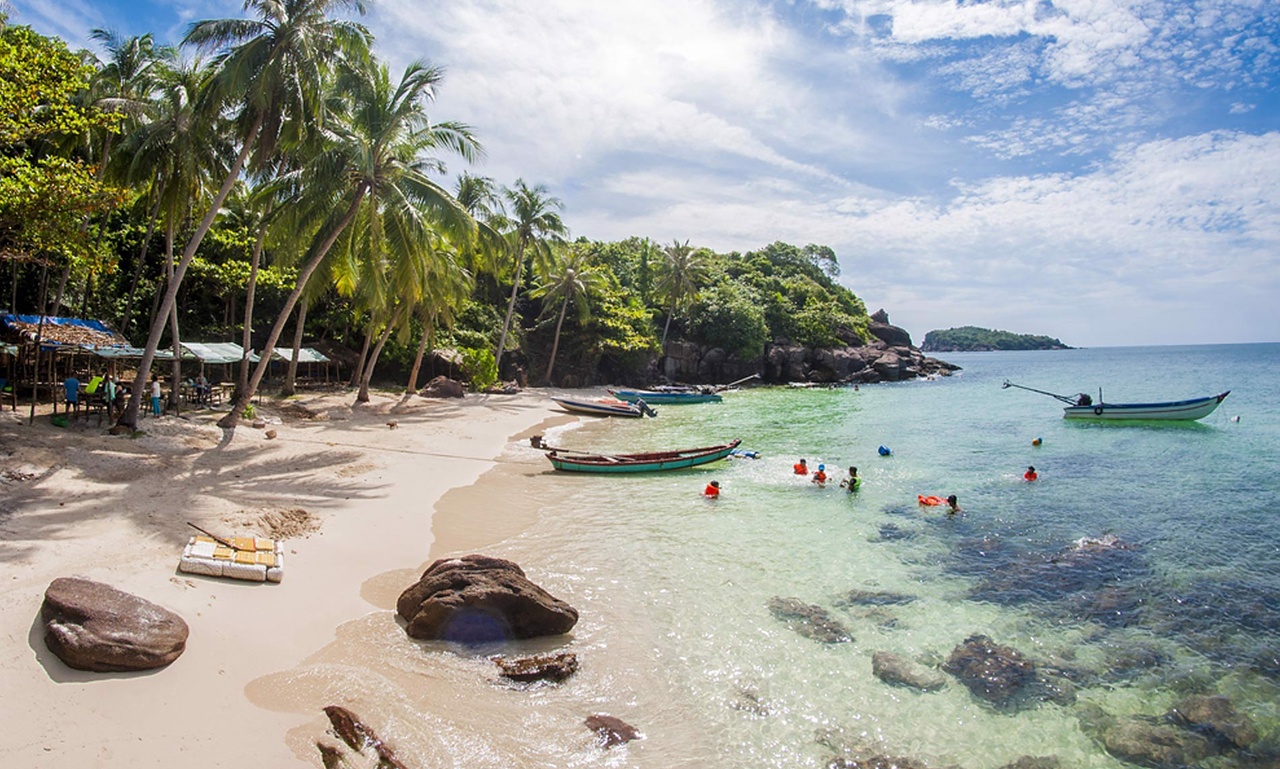 Tourists swimming in clear turquoise waters at a tropical beach in Phu Quoc, Vietnam