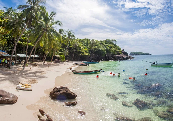 Tourists swimming in clear turquoise waters at a tropical beach in Phu Quoc, Vietnam