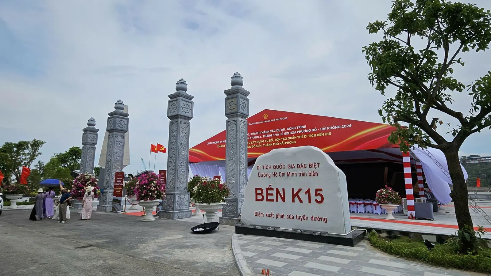 A stone sign identifying K15 Wharf as part of the Ho Chi Minh Trail at Sea stands beside carved entrance pillars.