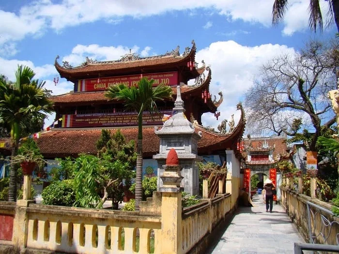 The curved roofs of Du Hang Pagoda rise above a walkway lined with stone pillars and palms.
