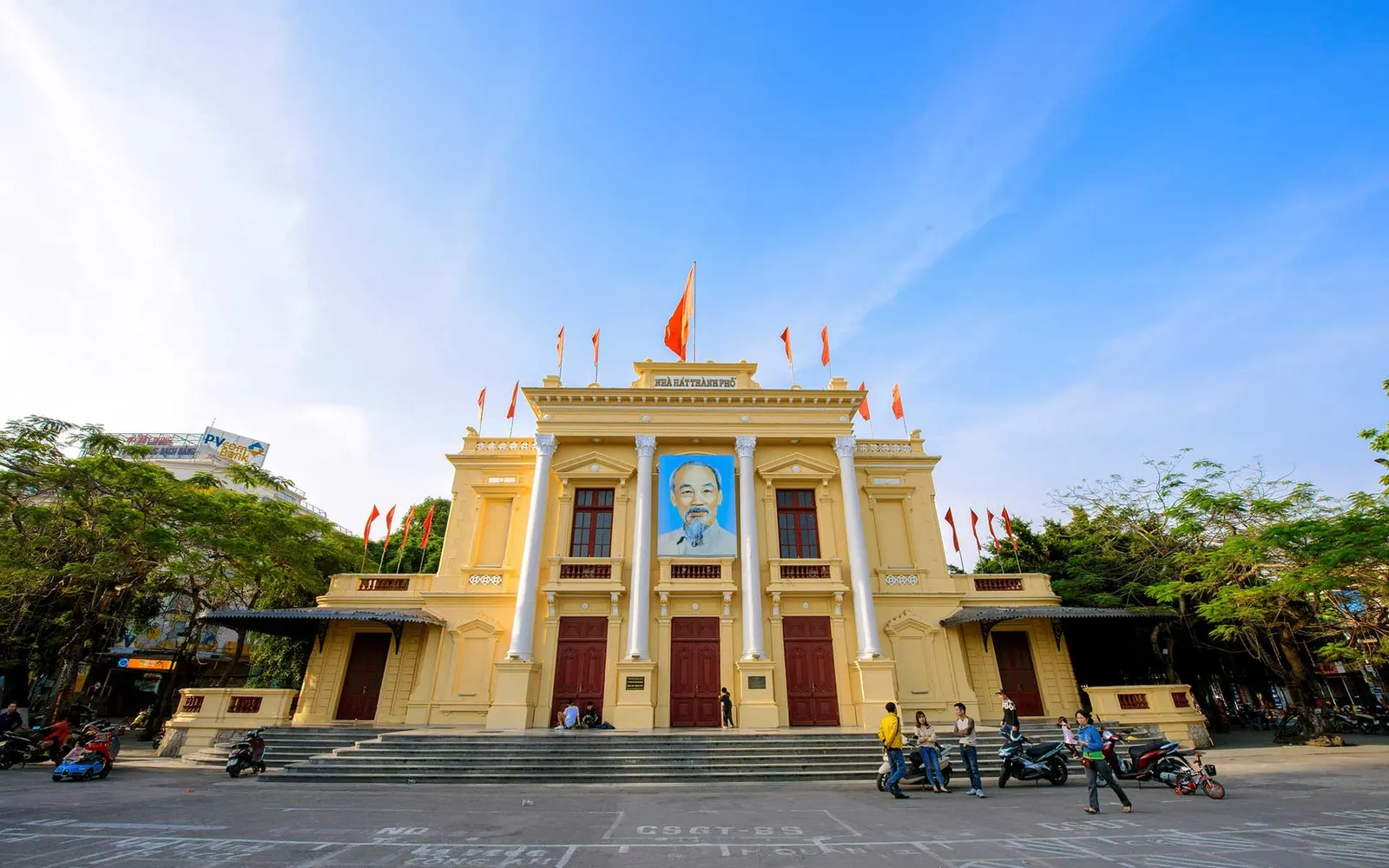 The yellow facade and white columns of Hai Phong Opera House face a broad public square.