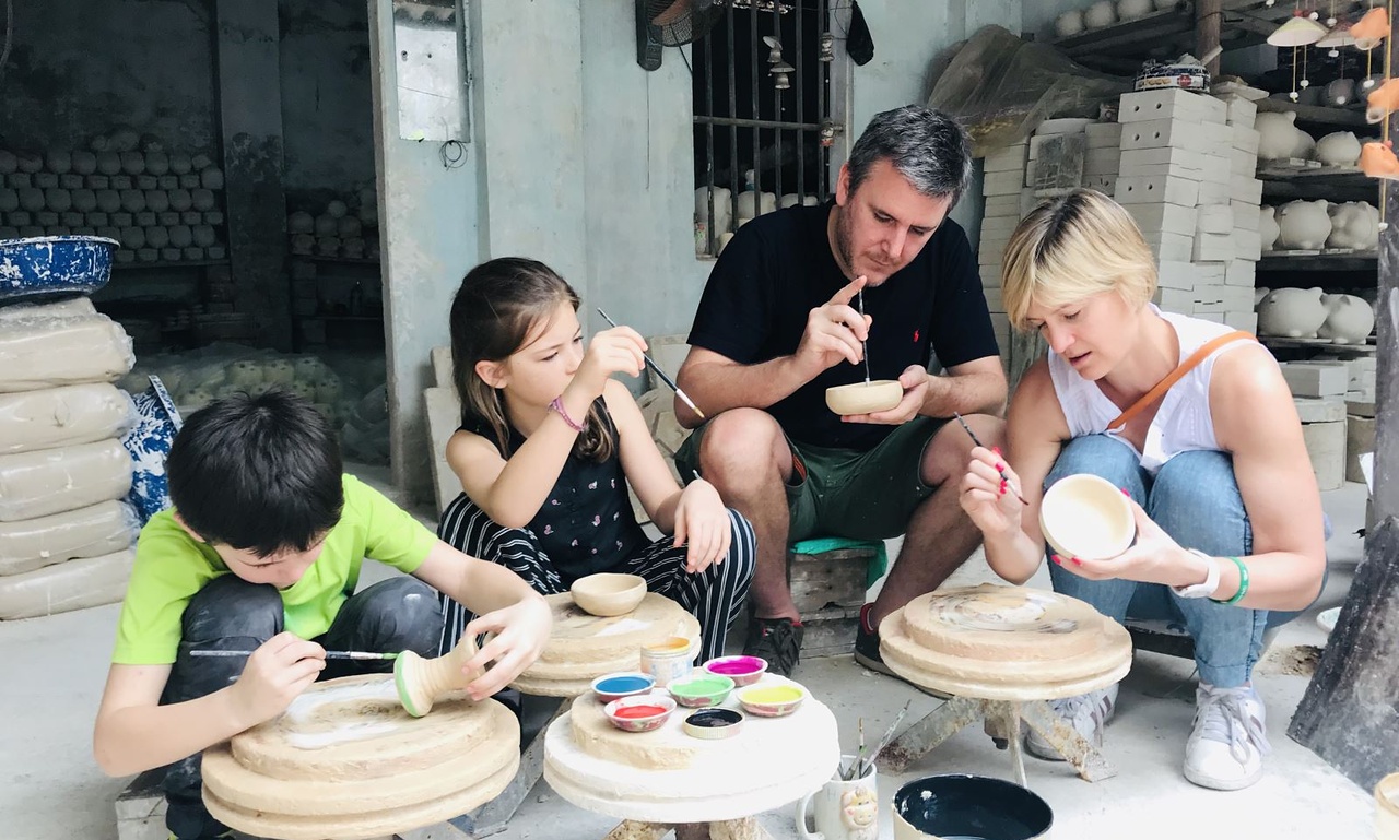 A family concentrates on painting ceramic bowls at a pottery workshop in Bat Trang, Vietnam