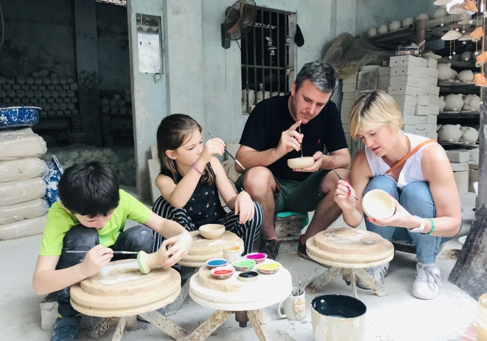 A family concentrates on painting ceramic bowls at a pottery workshop in Bat Trang, Vietnam