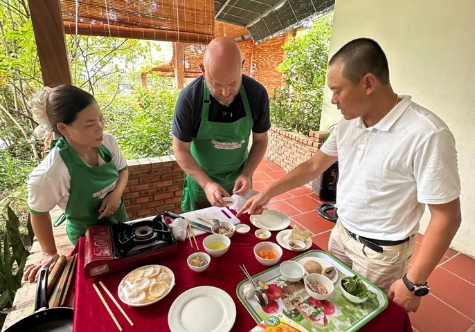 Family of travelers learning to cook traditional Vietnamese food at a culinary workshop in Hoi An, Vietnam