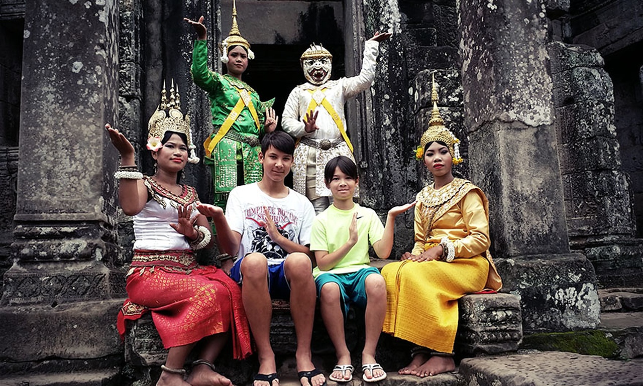 Family travelers with children experiencing a traditional Apsara dance performance at Angkor Wat, Cambodia