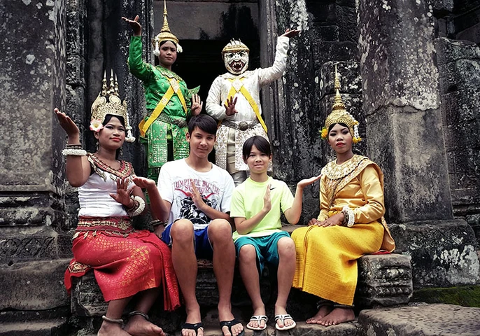Family travelers with children experiencing a traditional Apsara dance performance at Angkor Wat, Cambodia