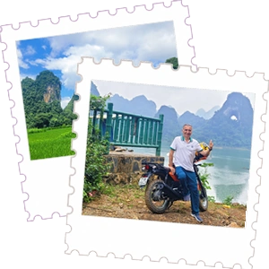 A mature male tourist sitting on a motorbike and giving a thumbs up, with a scenic lake and karst mountains in the background in Cao Bang, Vietnam